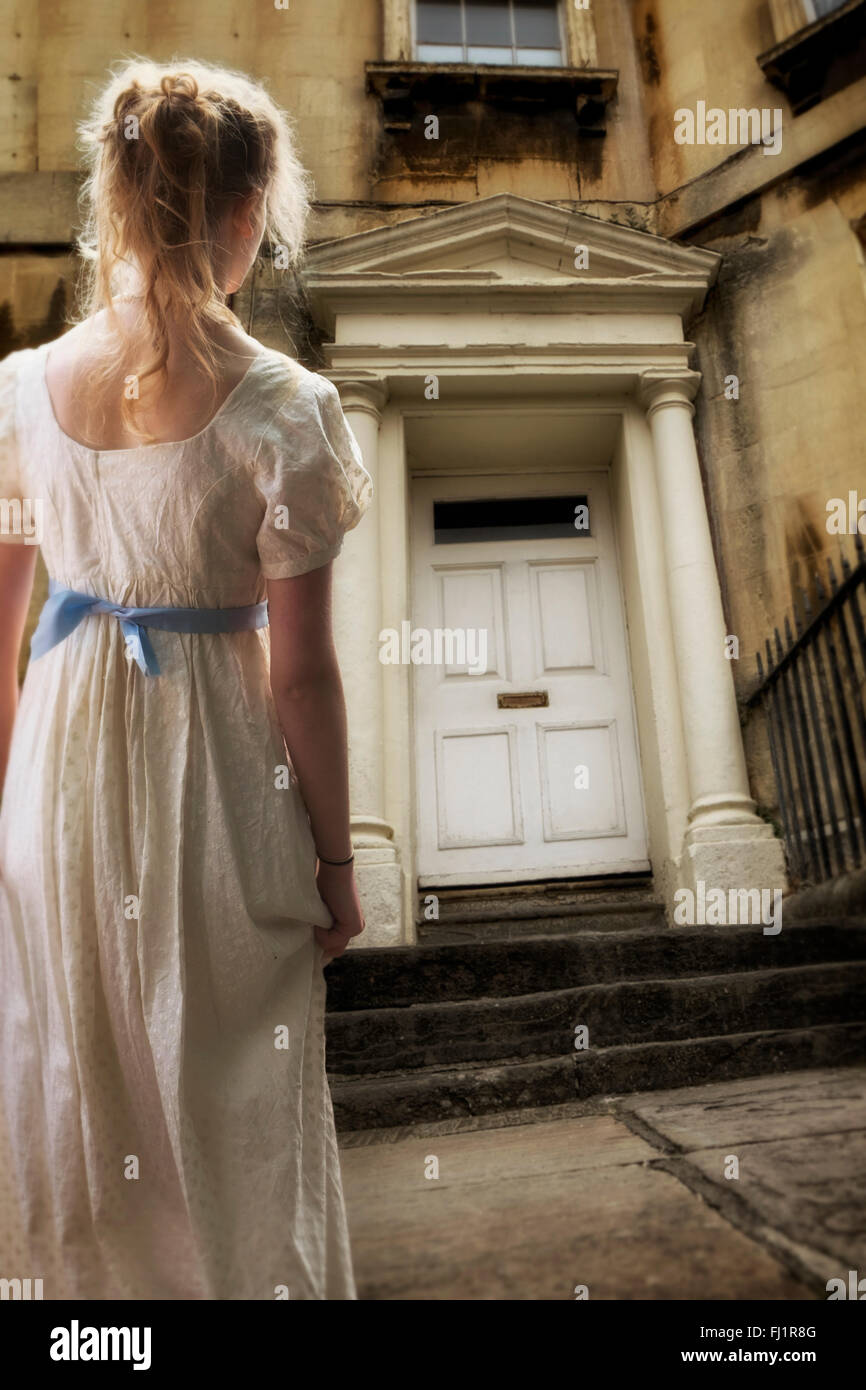 Regency dressed woman waiting outside a regency style house Stock Photo