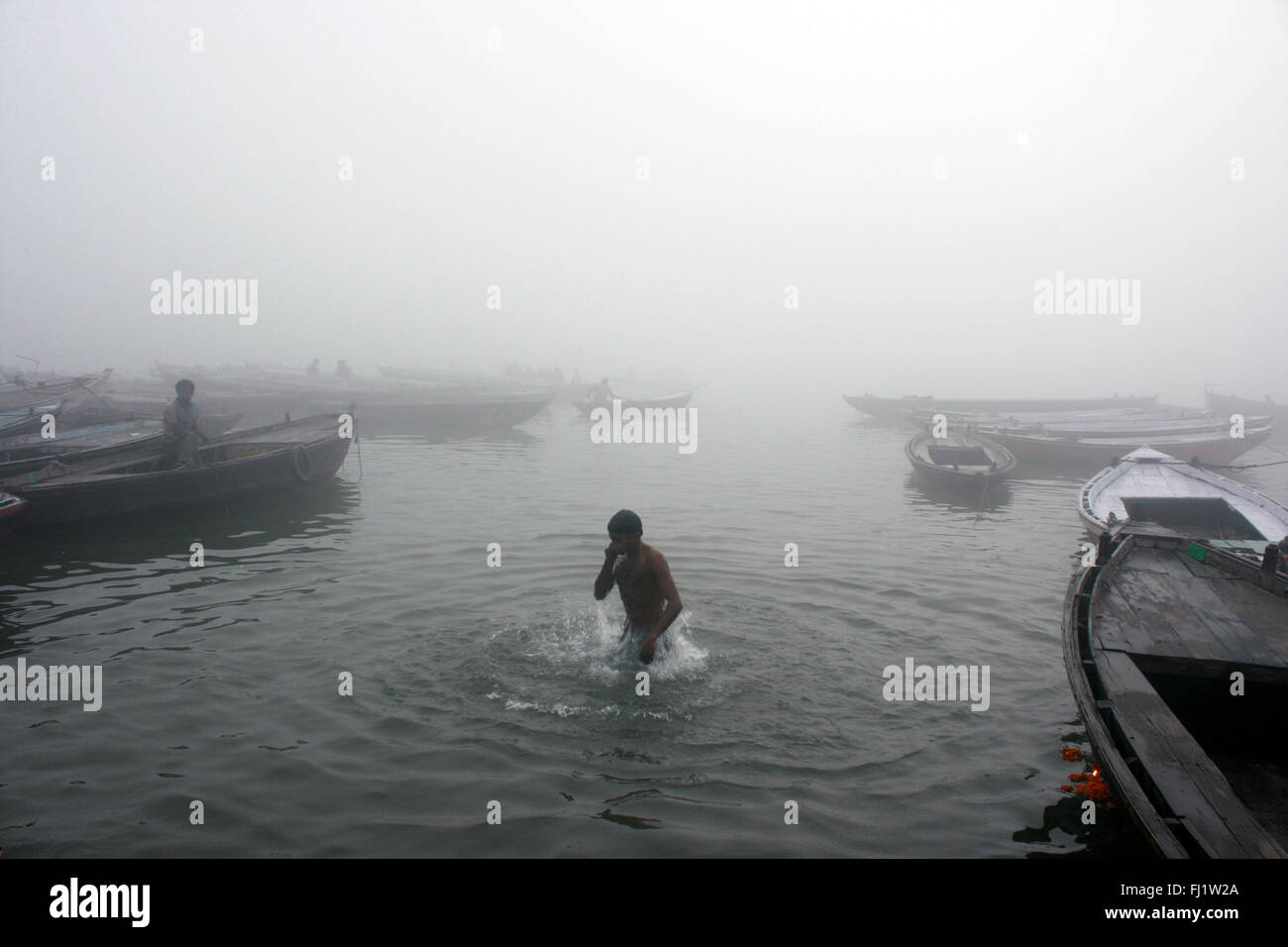 Man goes for a dip in holy water of the Ganges in Varanasi, India Stock Photo
