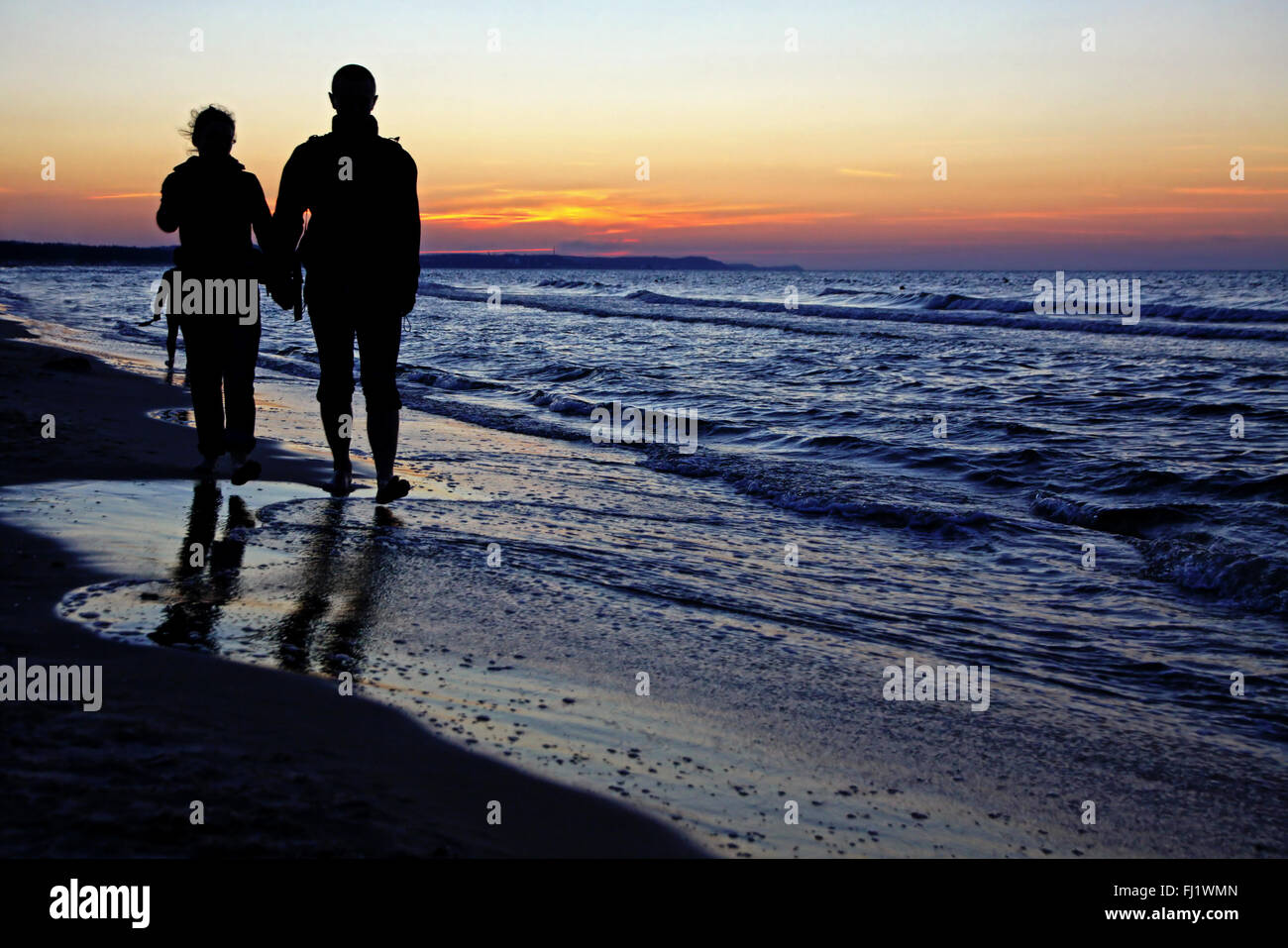 Couple of unrecognizable people enjoying a beach walk at sunset Stock Photo