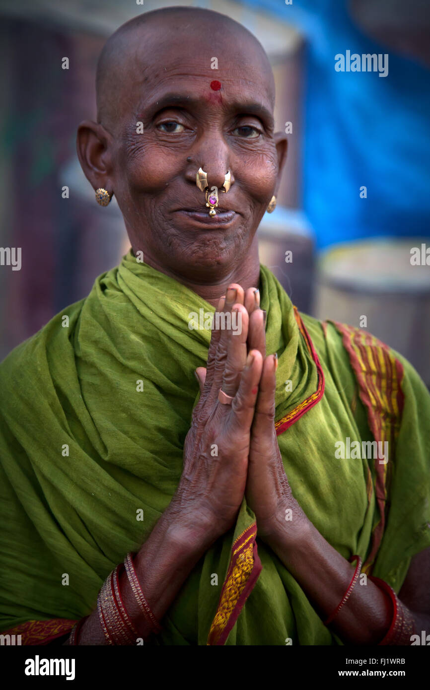 Stunning portrait of a pilgrim woman with bald head and tilak and Nose ring on Dashashwamedh Ghat in Varanasi, India Stock Photo
