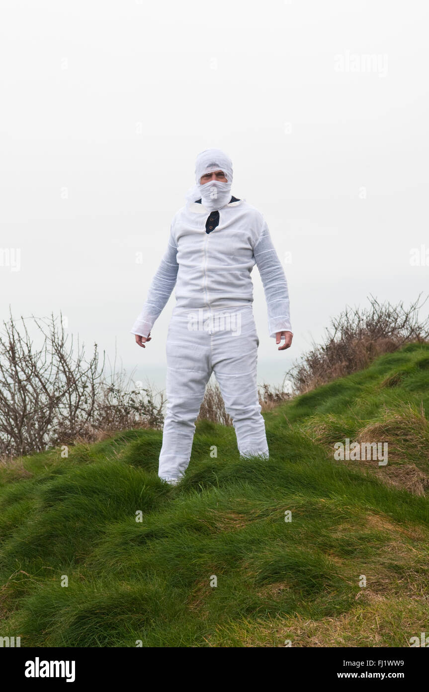 Man in a tight white boiler suit with his head in white bandages standing  in a field Stock Photo - Alamy