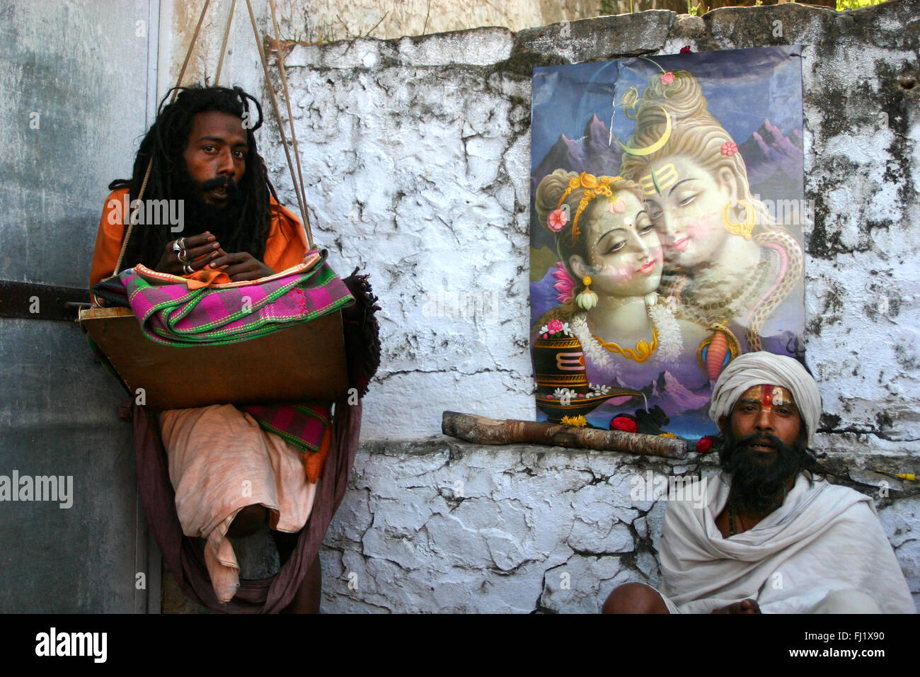Sadhus posing during Pushkar mela with poster of Shiva and Parvati Stock Photo