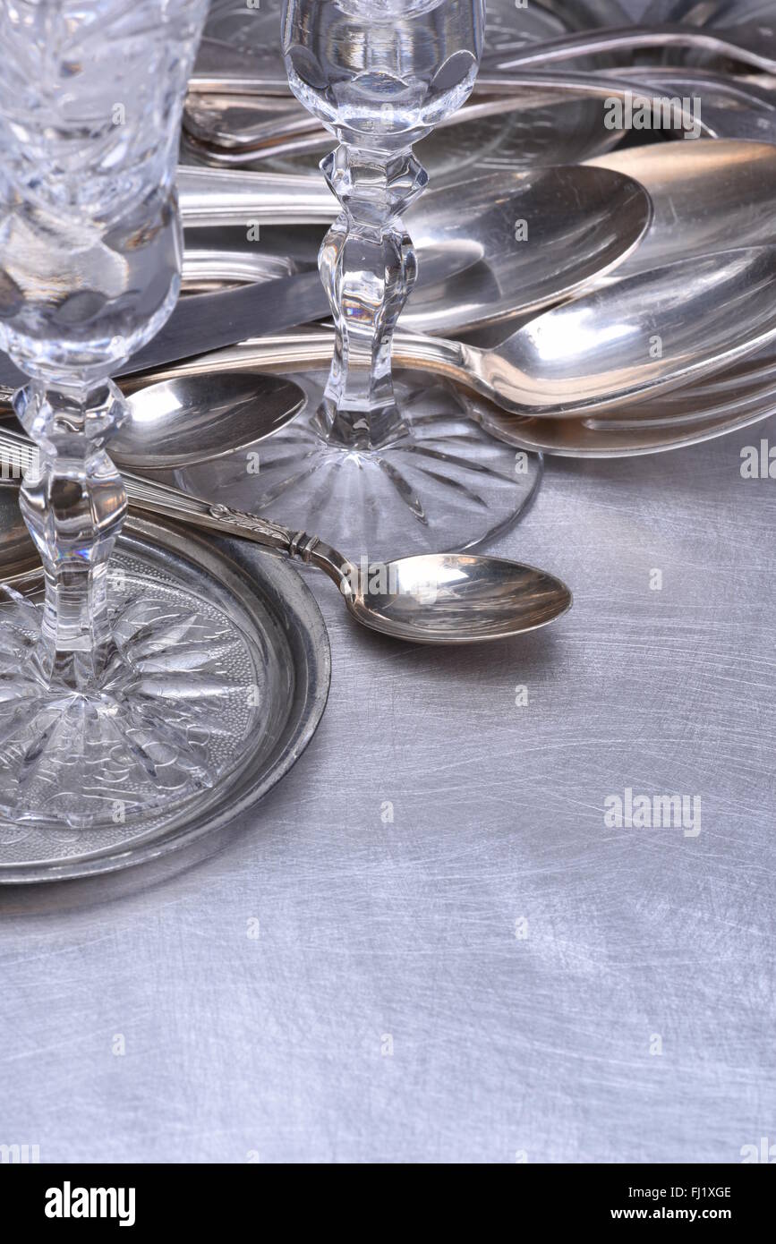 Silver table setting with fork, knife, spoon and glass on gray metal