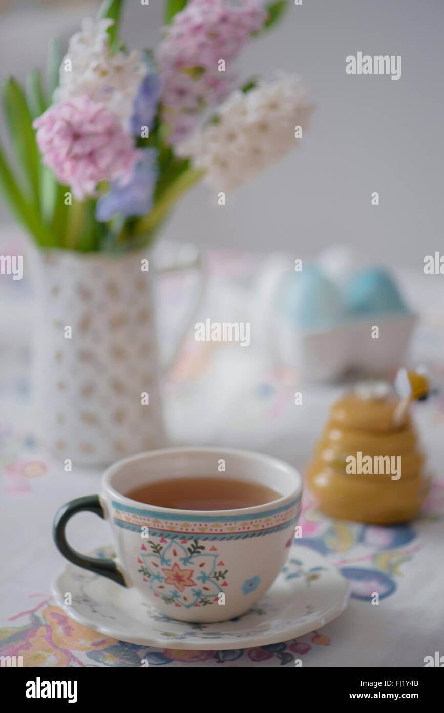 A full teacup with flowers and a honey pot Stock Photo