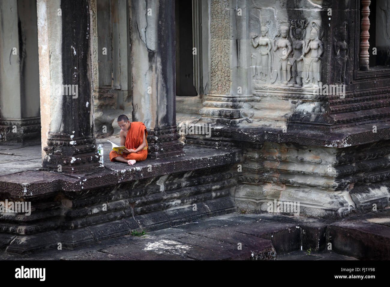 Buddhist monk reading inside Angkor vat temple, Cambodia Stock Photo