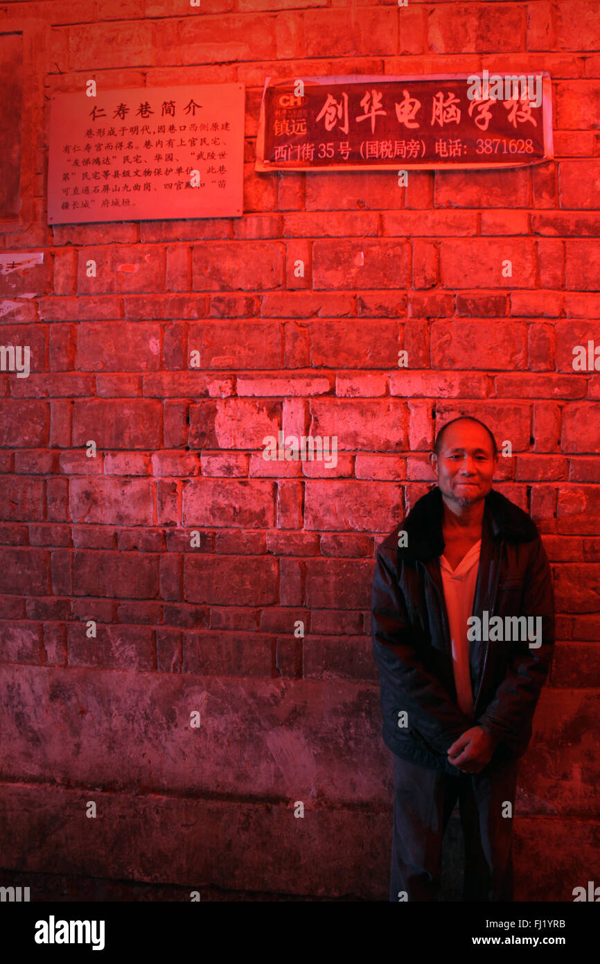 Chinese local man in a street of Zhenyuan, Guizhou,  at night with red light China Stock Photo