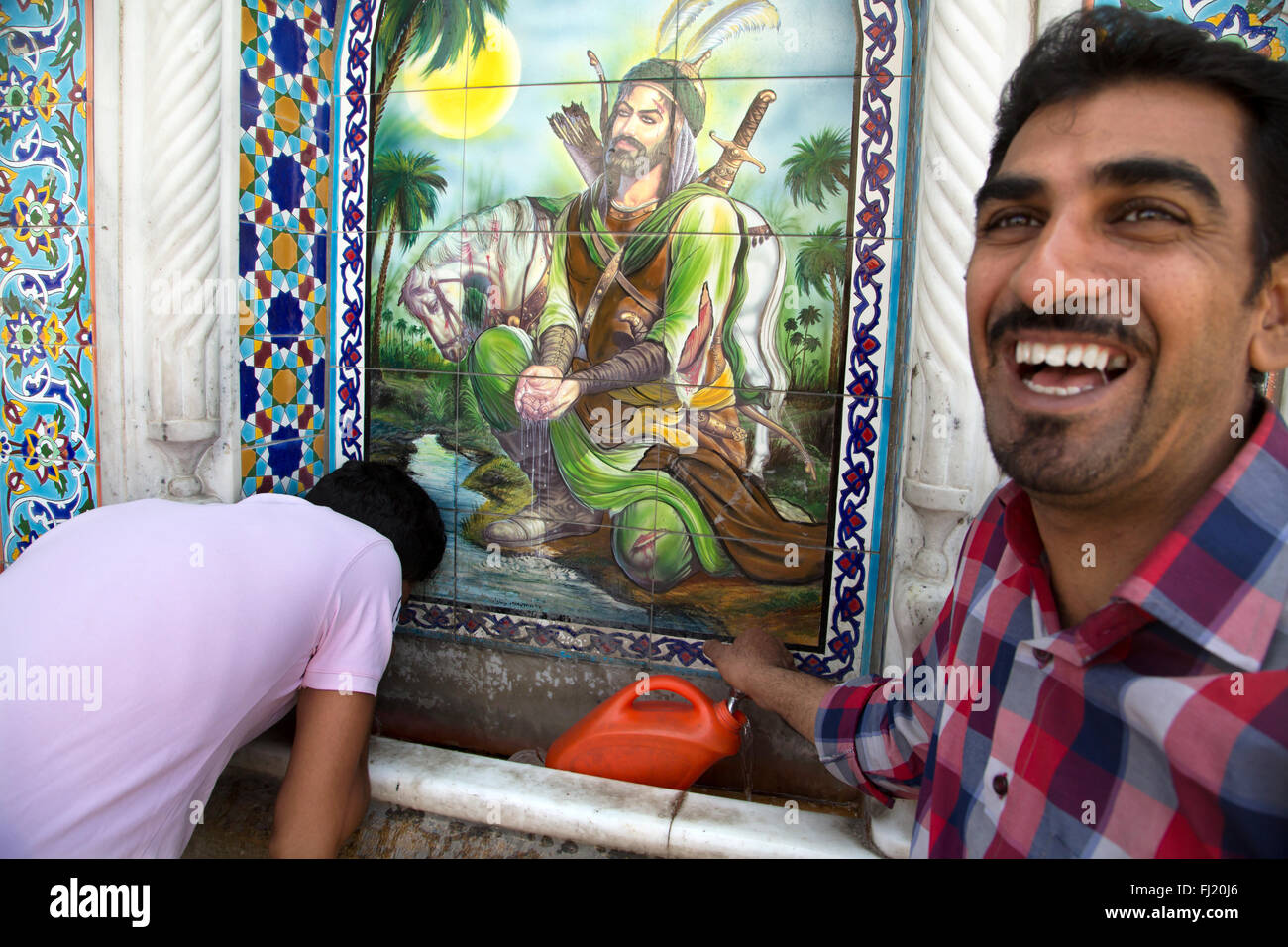 Portrait of Iranian man taking water to a fountain in Shiraz, Iran , with a portrait of Hazrat Abbas taking water in the Euphrates river Stock Photo