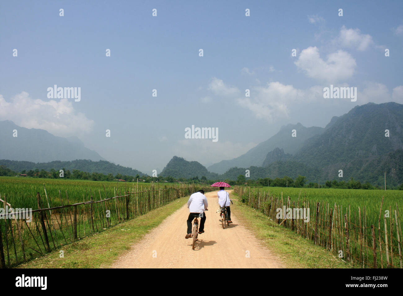 Two people cycling in typical landscape around Vang Vieng village , Laos , South East Asia Stock Photo