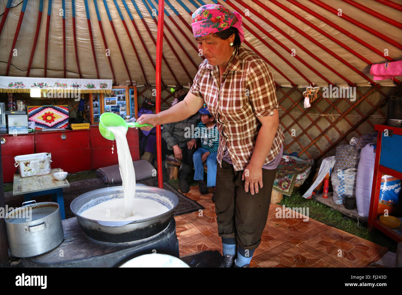 A nomad woman is boiling and preparing kumis traditional horse milk in a traditional yurt ger in Mongolia Stock Photo