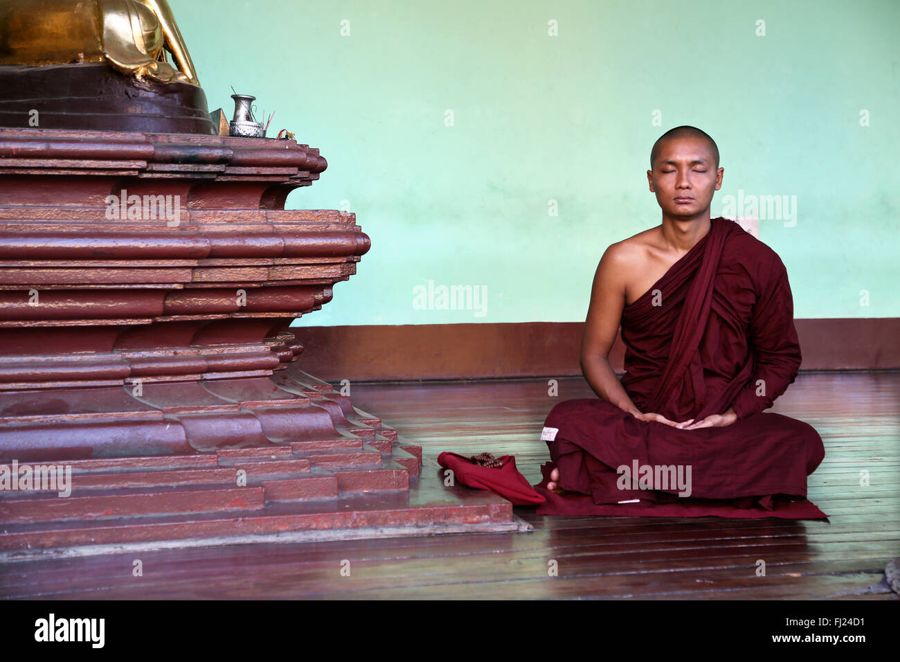 Buddhist monk meditating at Shwedagon pagoda, Myanmar Stock Photo