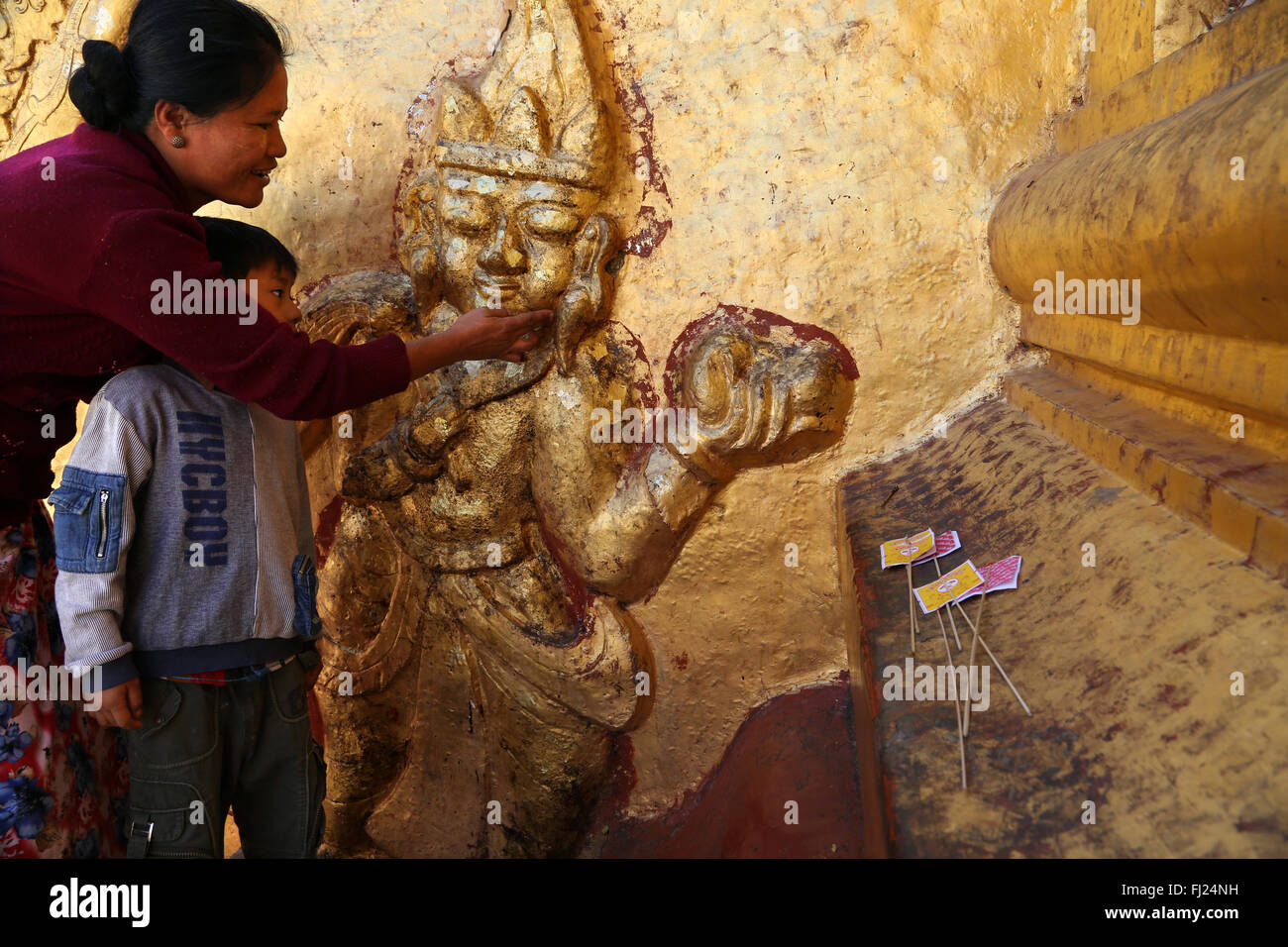 Mother and child painting Buddhist pagoda with goldleaves in Myanmar - Shwedagon pagoda in Rangoon Stock Photo