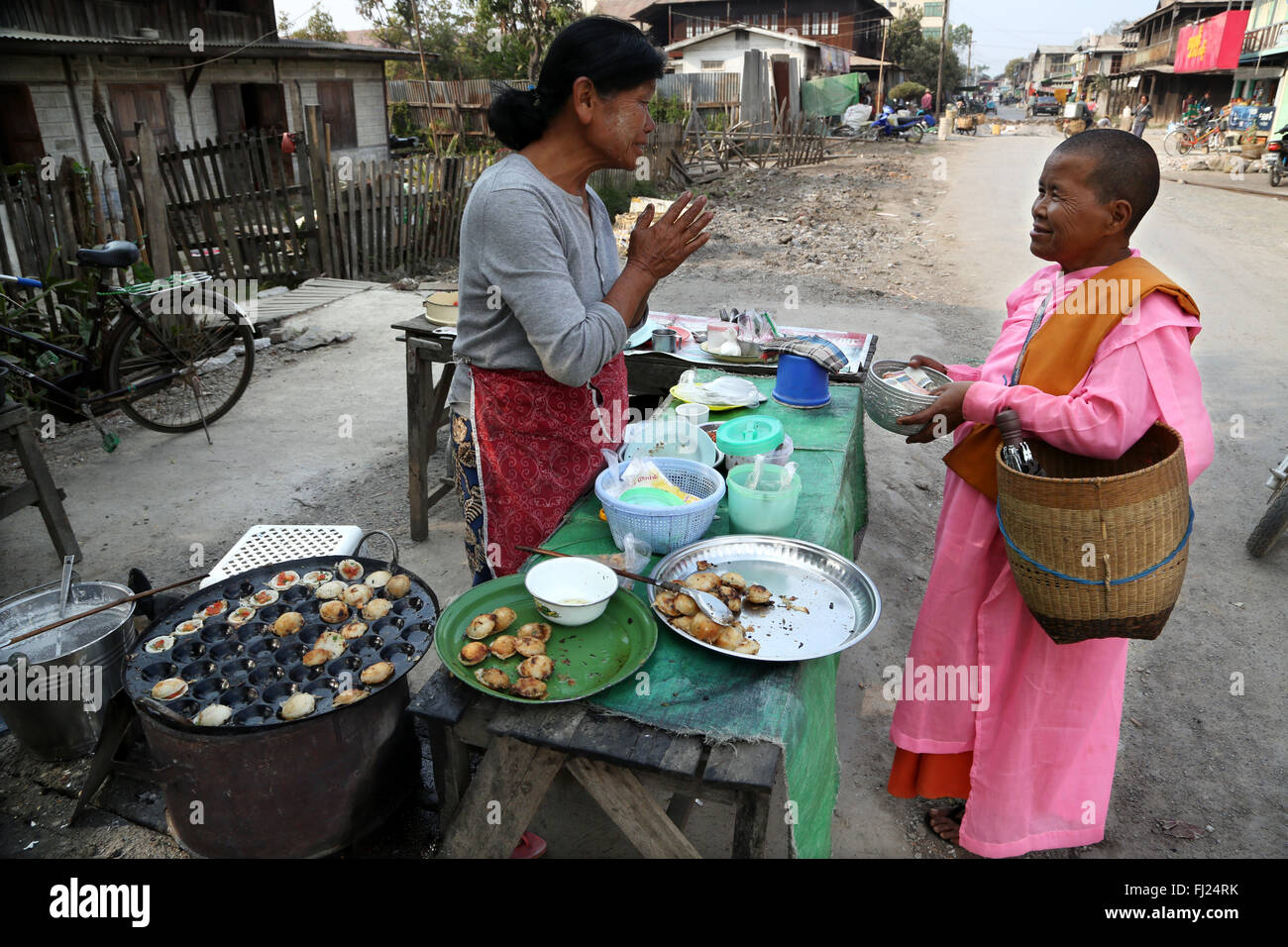 Lady giving food to a buddhist nun in the morning in Myanmar Stock Photo
