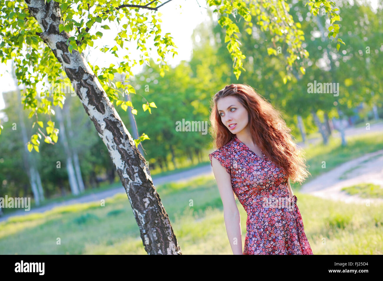 Beautiful red-haired girl in dress posing in nature Stock Photo