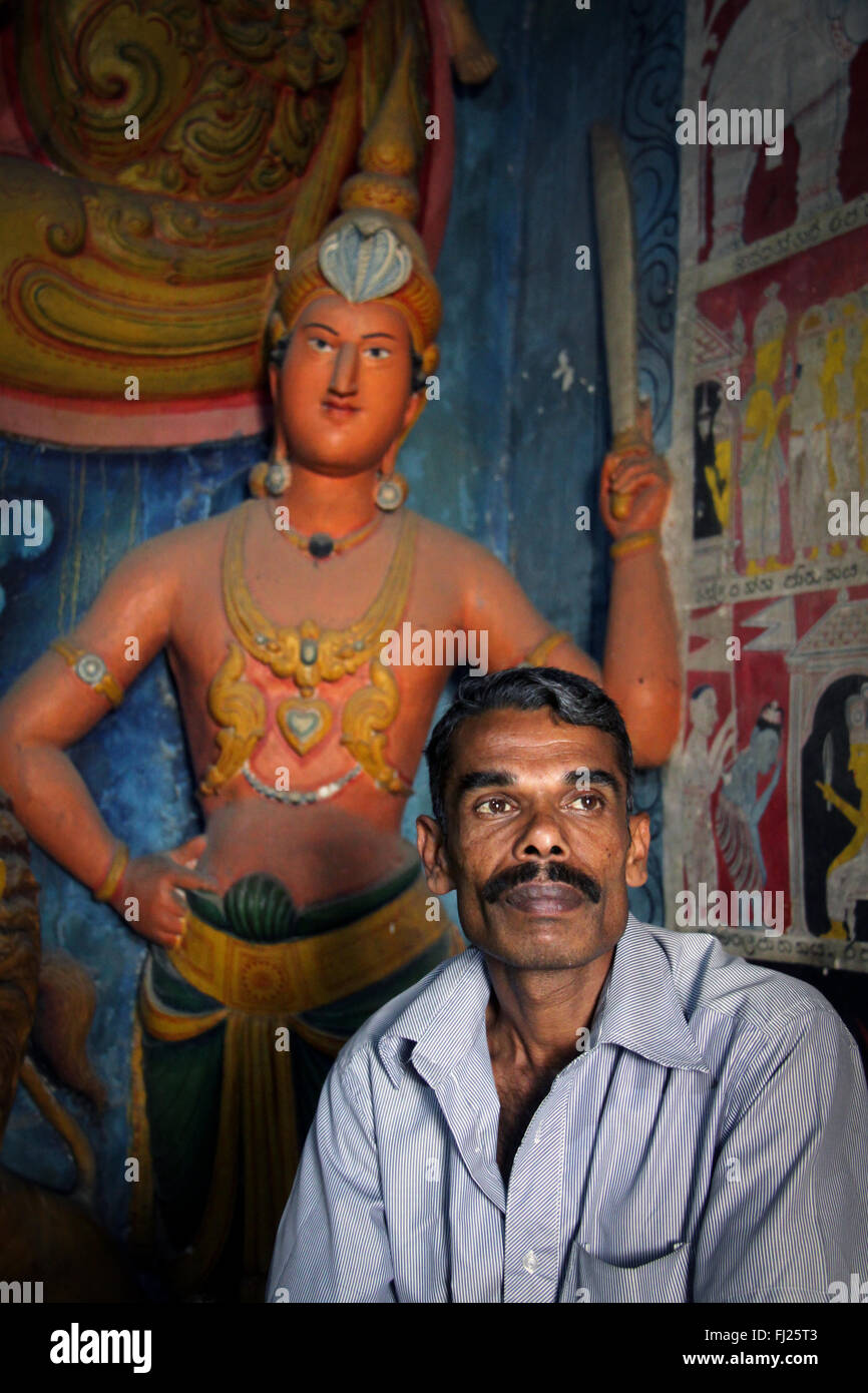 Portrait of man in a Buddhist temple with carving behind him,  in Sri Lanka Stock Photo