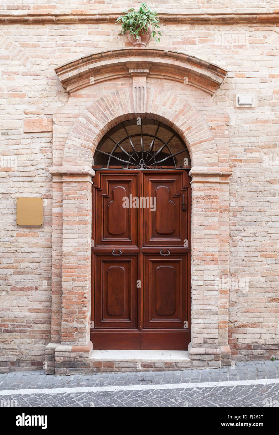Brown wooden door with arch in old stone wall, background photo texture ...