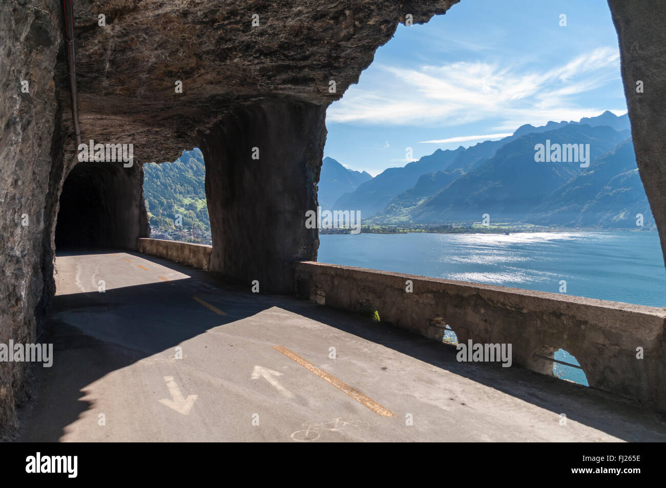 Old Axenstrasse road in a tunnel with large windows offering a view over Lake Lucerne and the Swiss Alps. Stock Photo