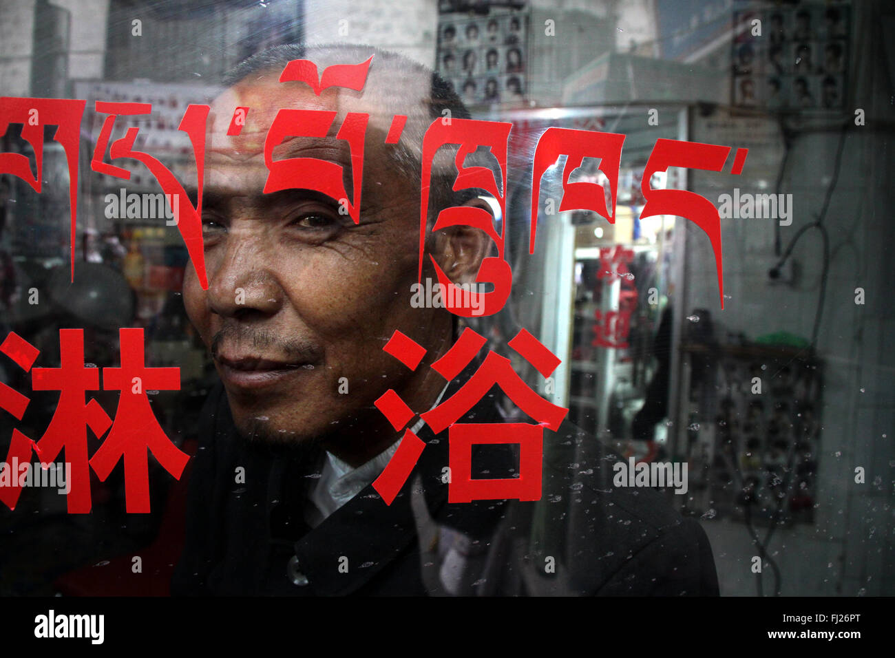 Portrait of man in the center of Lhasa with Tibetan writings on a glass Stock Photo
