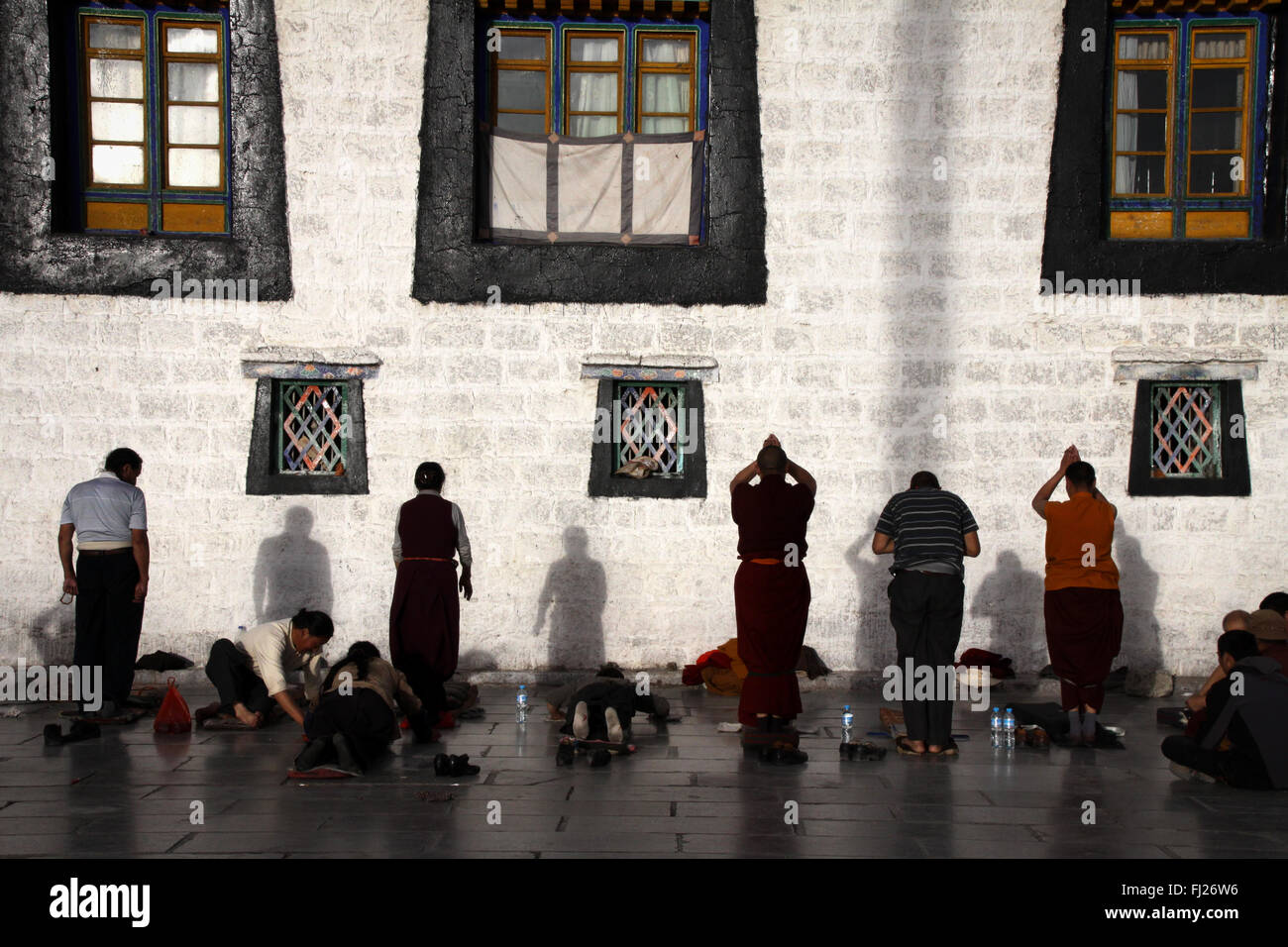 People praying by sunset in the center of Lhasa in front of monastery wall, Tibet Stock Photo