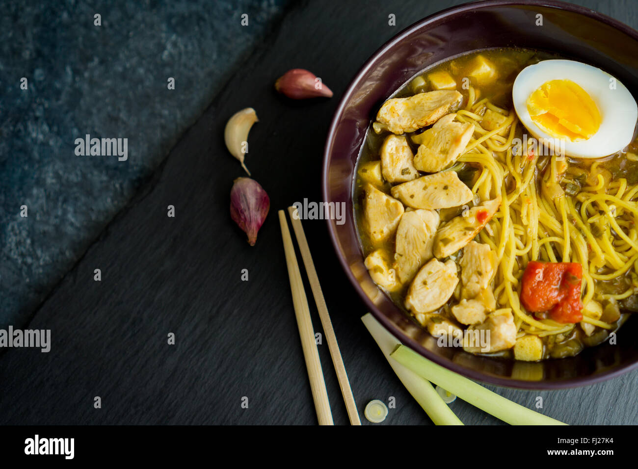 Asian dish ramen, with chicken, noodles and eggs, top view, on a black