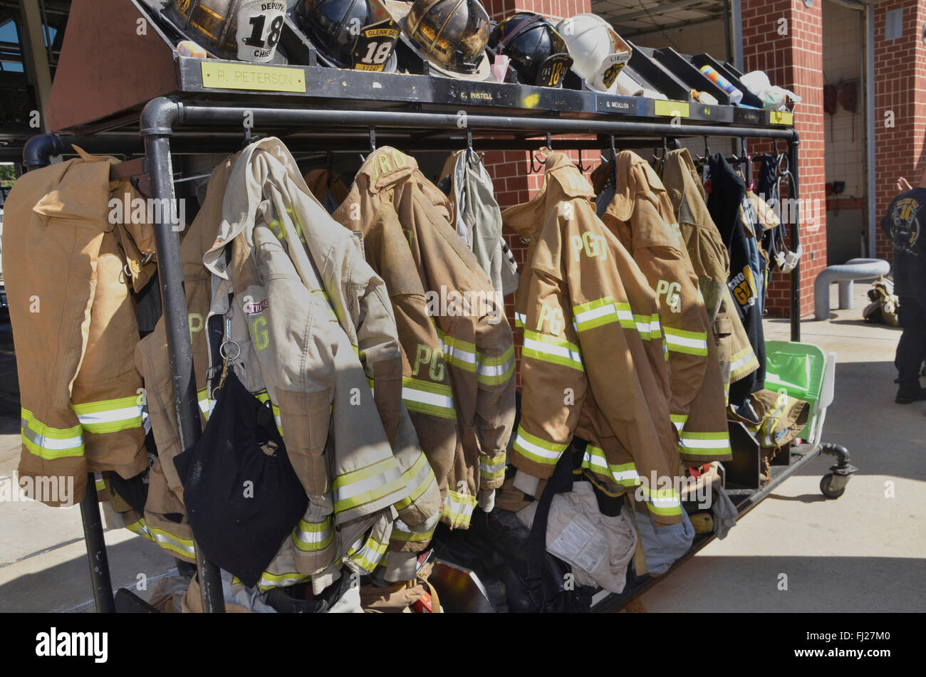 firefighters turnout gear hanging on racks outside Stock Photo