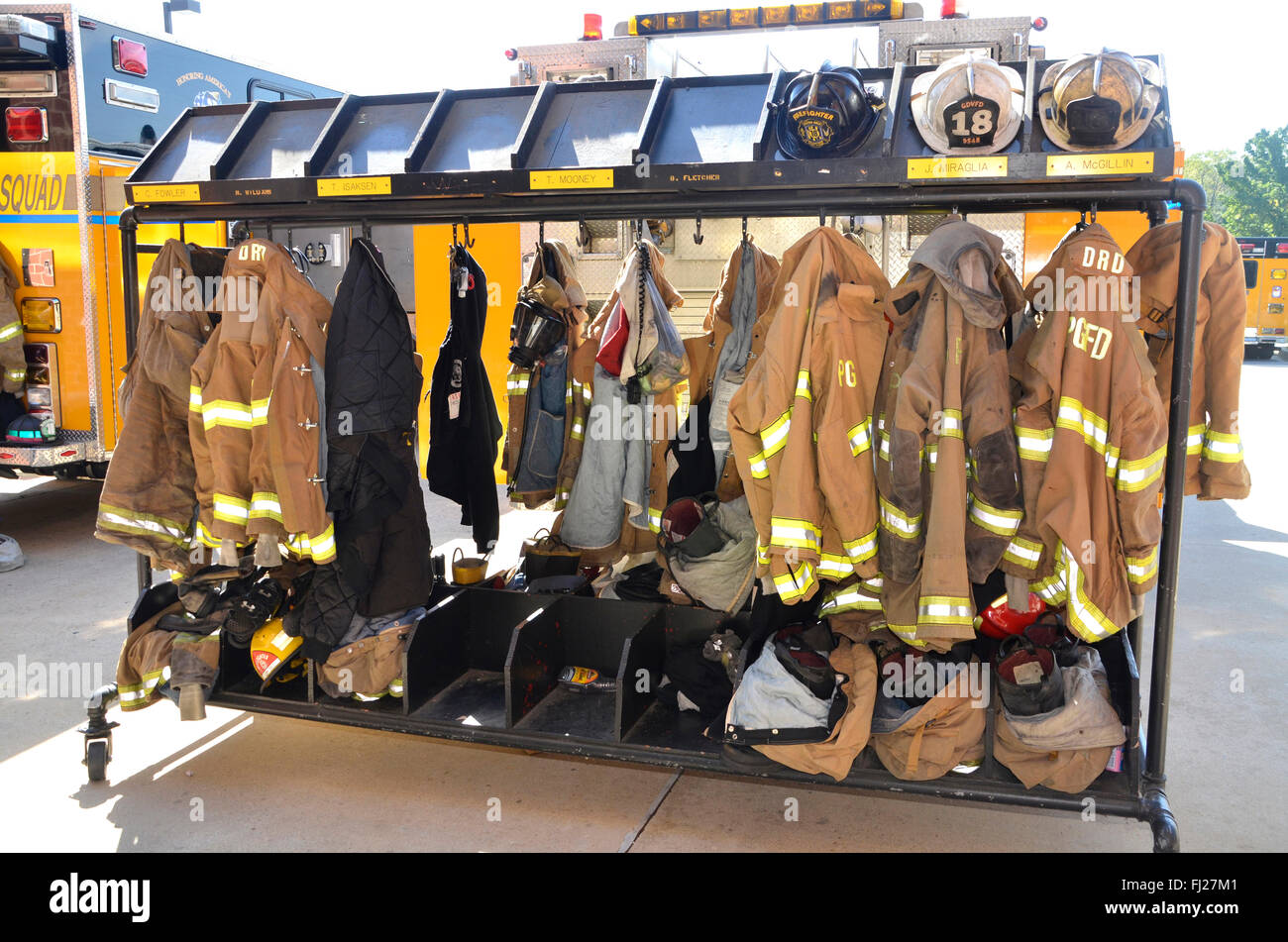 firefighters turnout gear hanging on racks outside Stock Photo