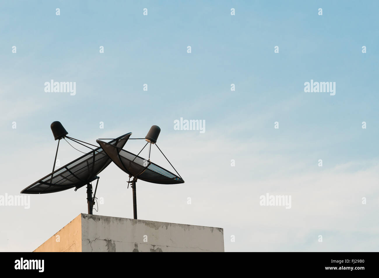 Two satellite dishes during sunset with copy space on blue sky background Stock Photo