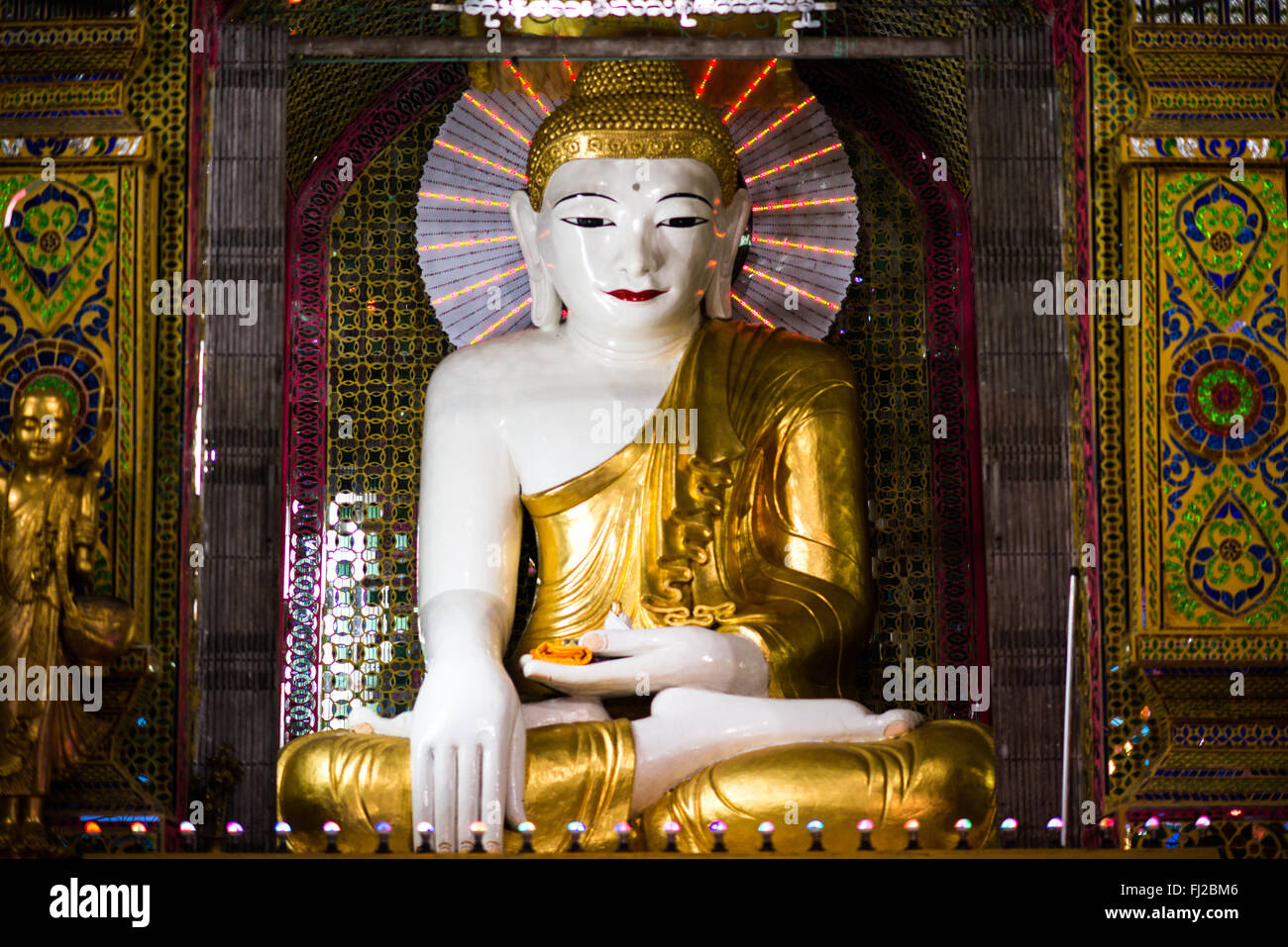 Buddha Statue Sutaungpyei Pagoda Mandalay Myanmar // MANDALAY, Myanmar — A Buddha statue stands within the Sutaungpyei Pagoda (also known as Su Taung Pyae Pagoda) complex at the summit of Mandalay Hill. The pagoda was constructed during the mid-19th century reign of King Mindon, coinciding with the establishment of Mandalay as the royal capital in 1857. The name Sutaungpyei translates to 'wish-fulfilling,' reflecting the site's spiritual significance as a place where devotees seek blessings and make merit. The pagoda sits at the highest point of Mandalay Hill, a site of profound religious impo Stock Photo
