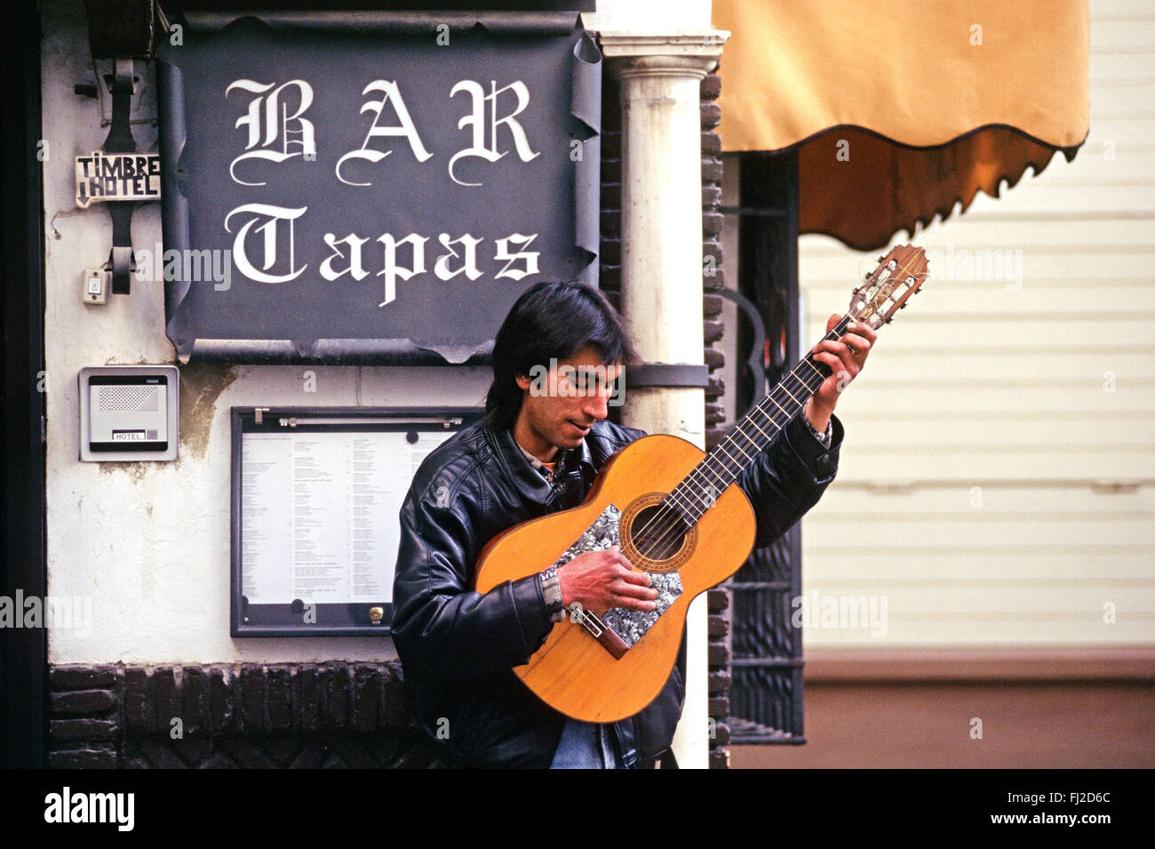 A Spaniard plays FLAMENCO GUITAR outside a restaurant in SEVILLA - SPAIN Stock Photo