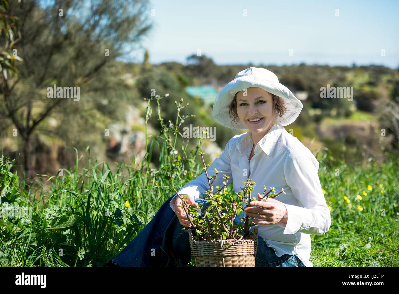A mature woman in white hat sitting with plant in pot outdoors Stock ...