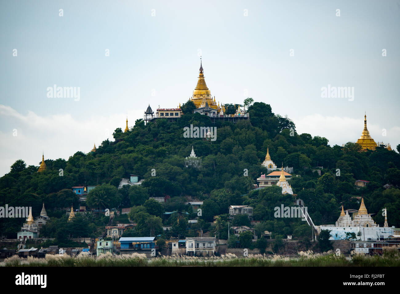 MANDALAY, Myanmar - The gold covered umbrella of on the many temples in the hills of Sagaing, near Mandalay, as seen from across the Ayeyarwaddy River. Stock Photo