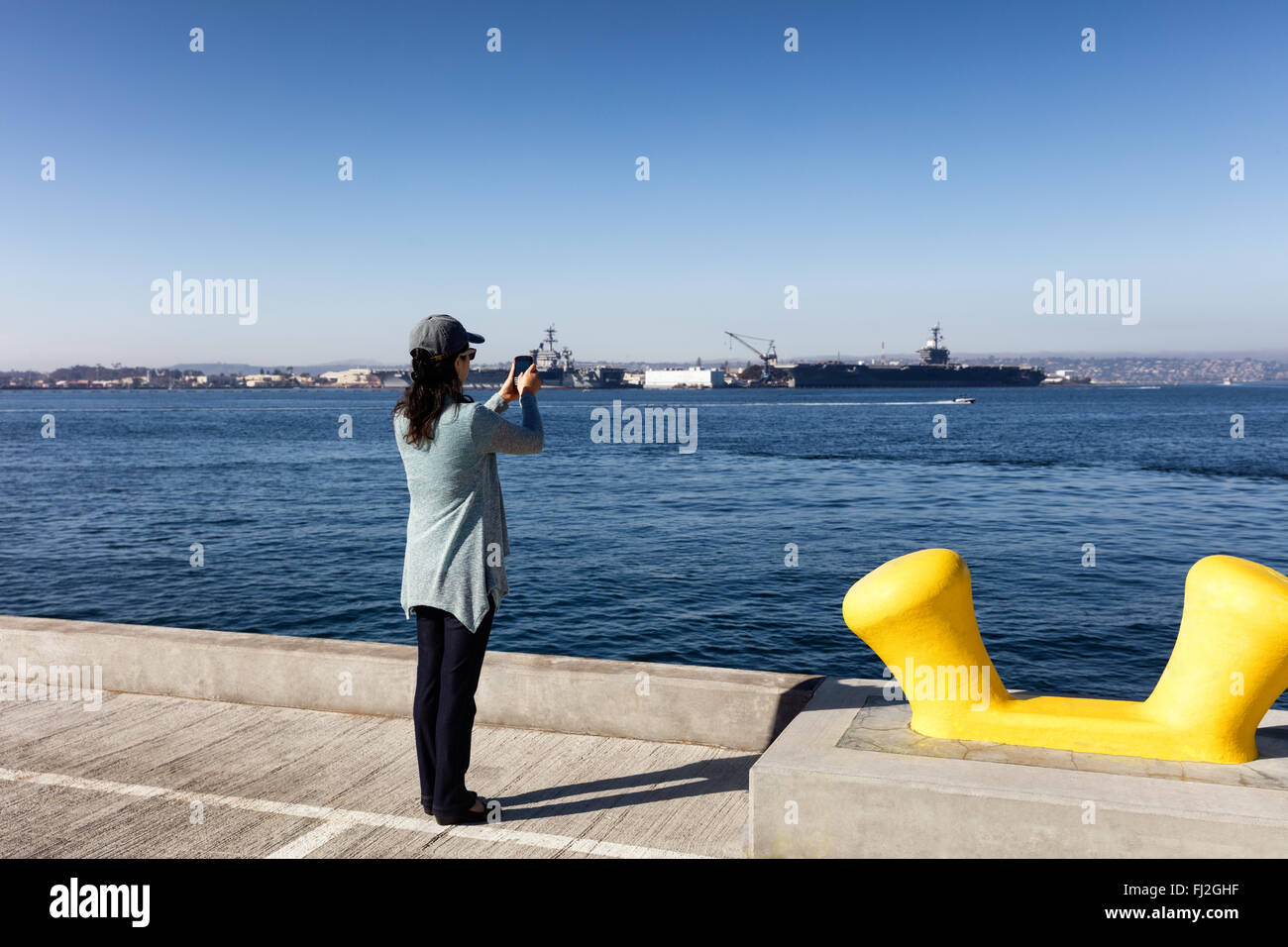 Back view of a woman taking photos with cell phone San Diego bay in Southern California. Stock Photo