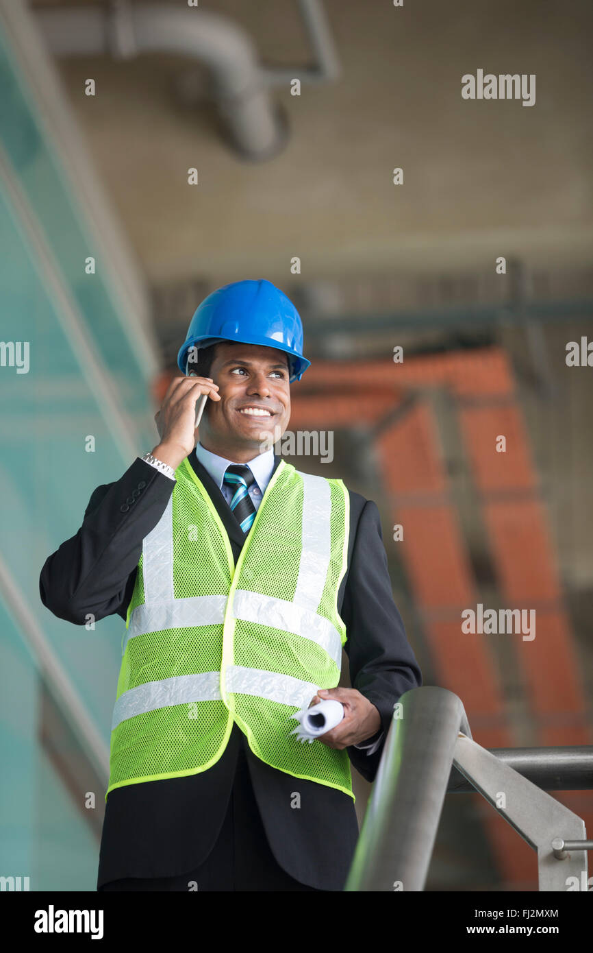 Portrait of a male Indian Architect or industrial engineer at work using phone. Stock Photo