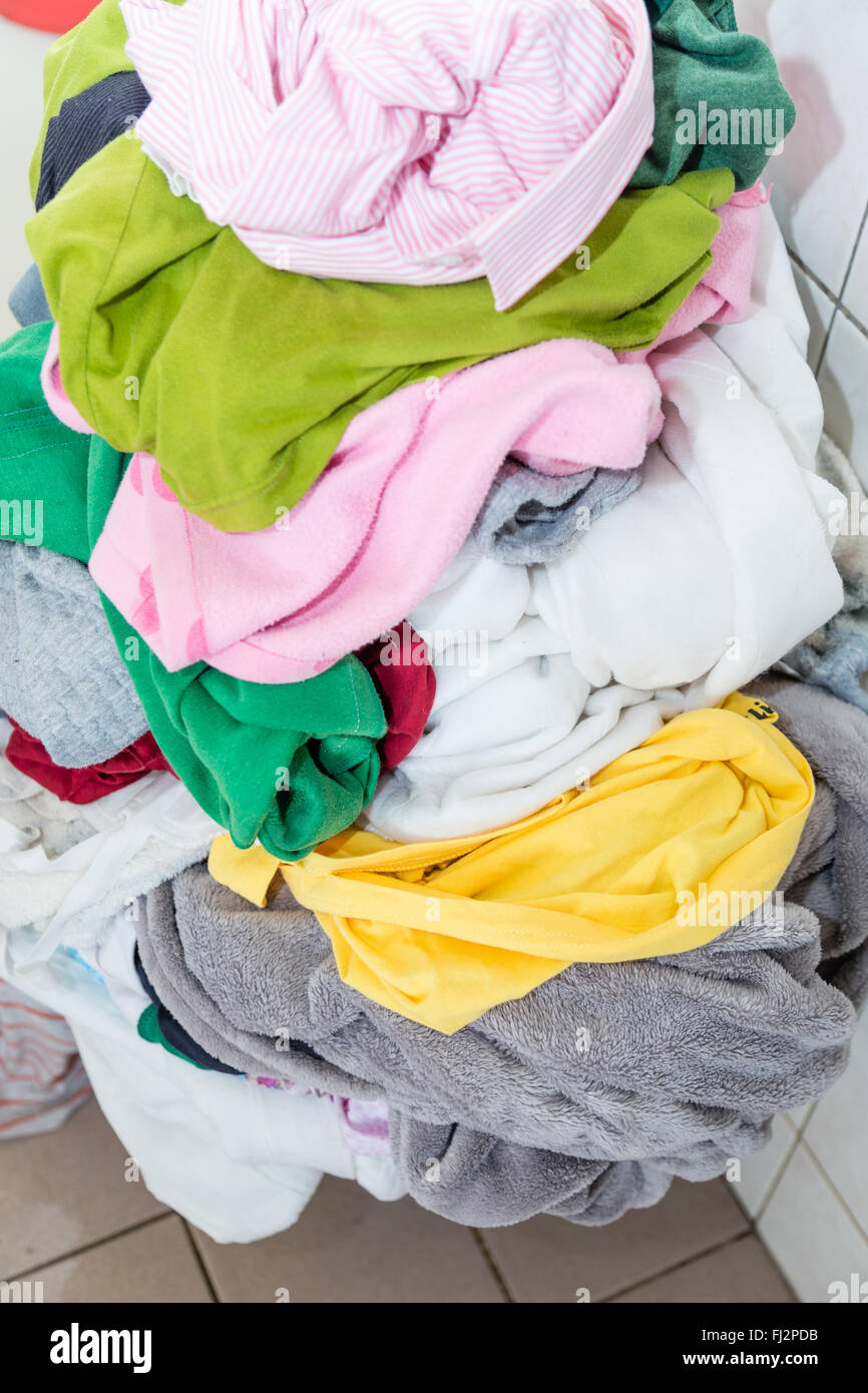 Laundr basket overflowing with dirty clothes and blankets Stock Photo