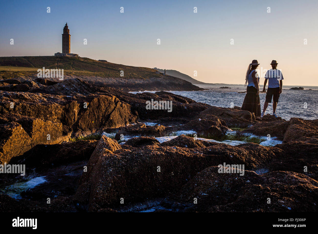 Couple in Punta Herminia gardens,in background Tower of Hercules, Roman lighthouse, Coruña city, Galicia, Spain Stock Photo