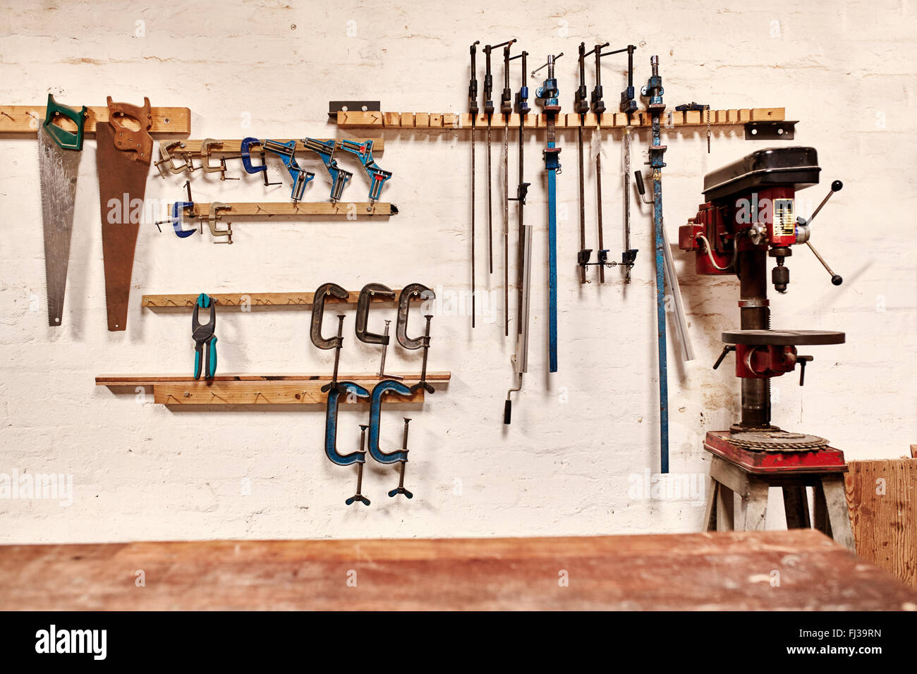 Workshop wall with tools in rows alongside a drill press Stock Photo