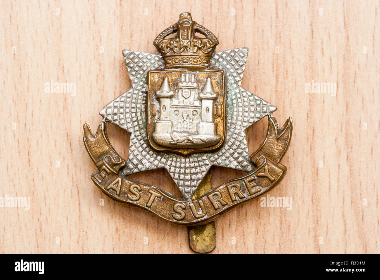 First world war, the great war. Regalia. East Surrey Regiment cap badge on wooden grain background. Stock Photo