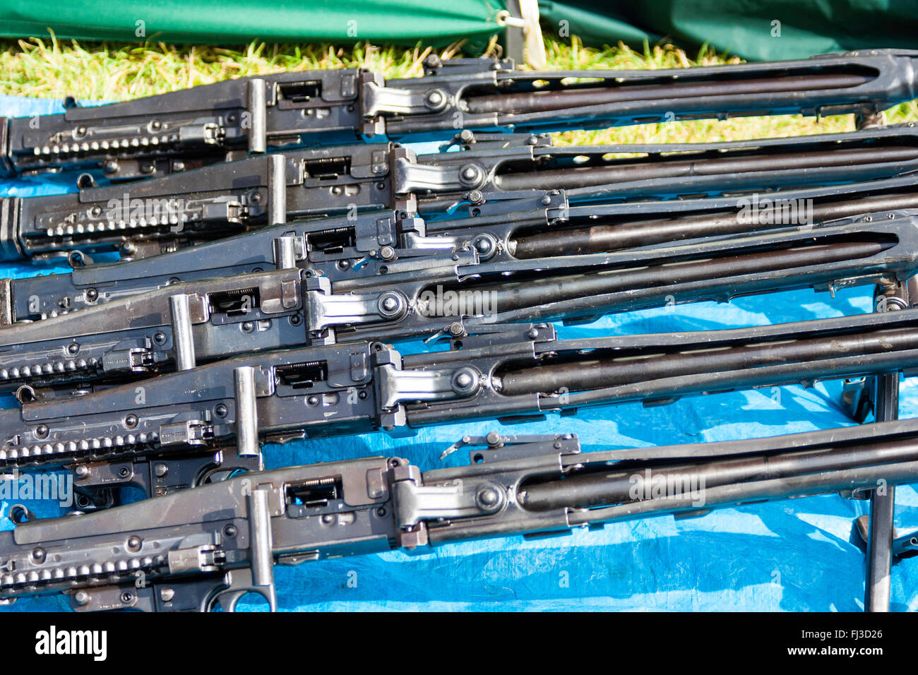 War and peace show market place area. Row of five German second world war MG42 machine guns for sale on blue mat. Close up. Stock Photo