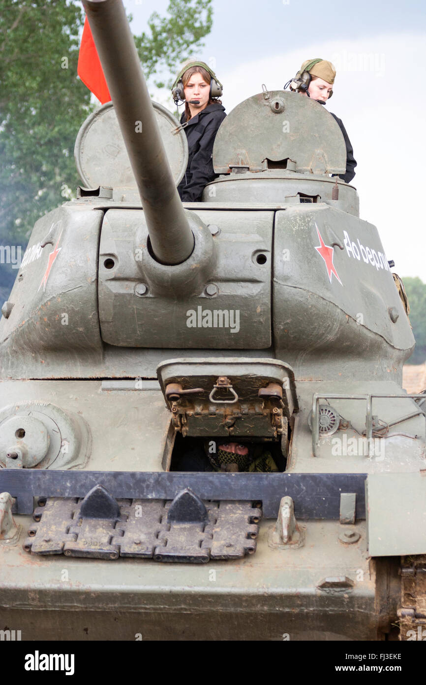 War and peace show, England. Second world war re-enactment. Russian T34 tank, facing viewer, drivern by two teenage women in turret. Red flag flying. Stock Photo