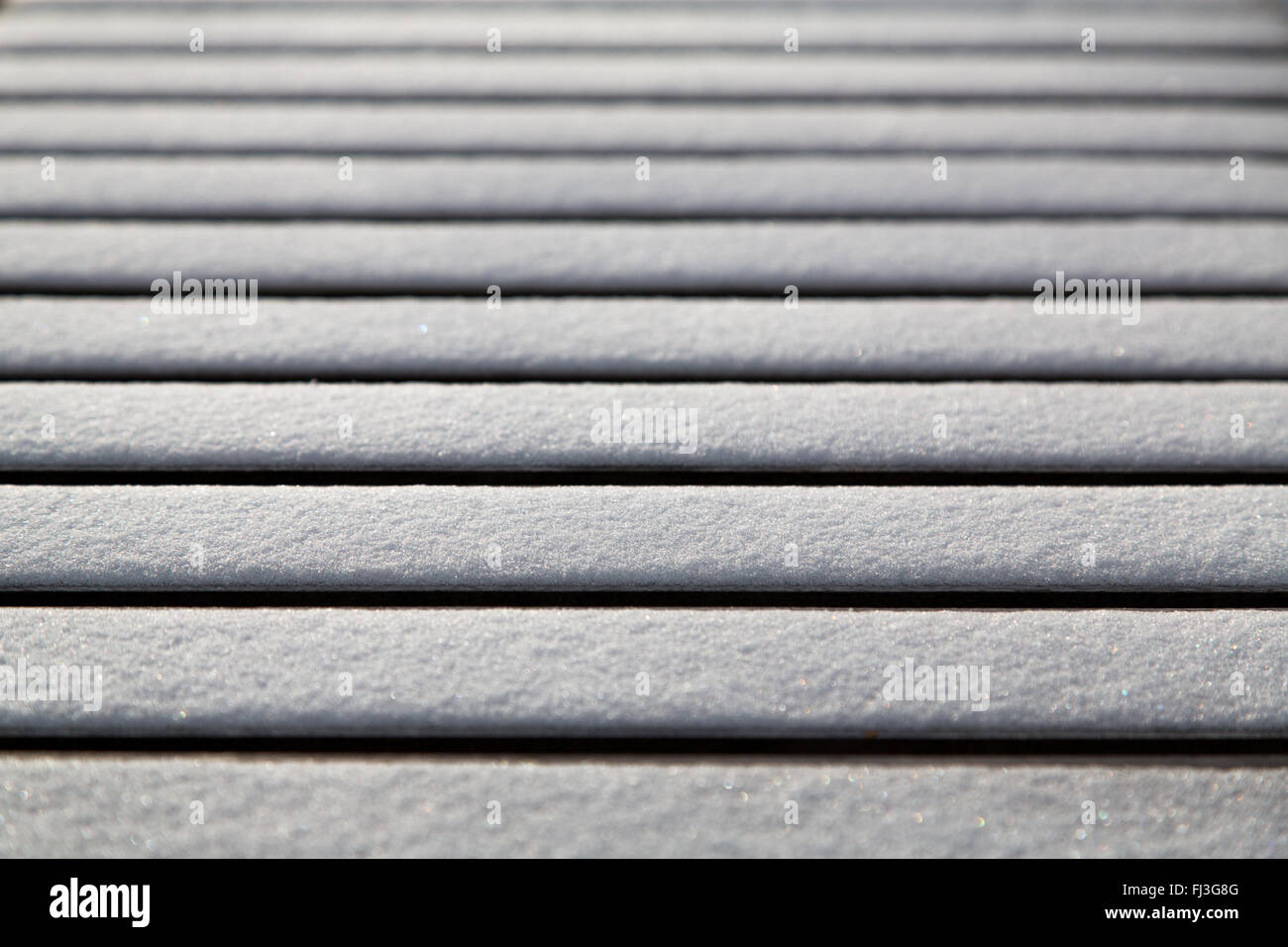 Abstract of snow on bench with only one slat in focus Stock Photo