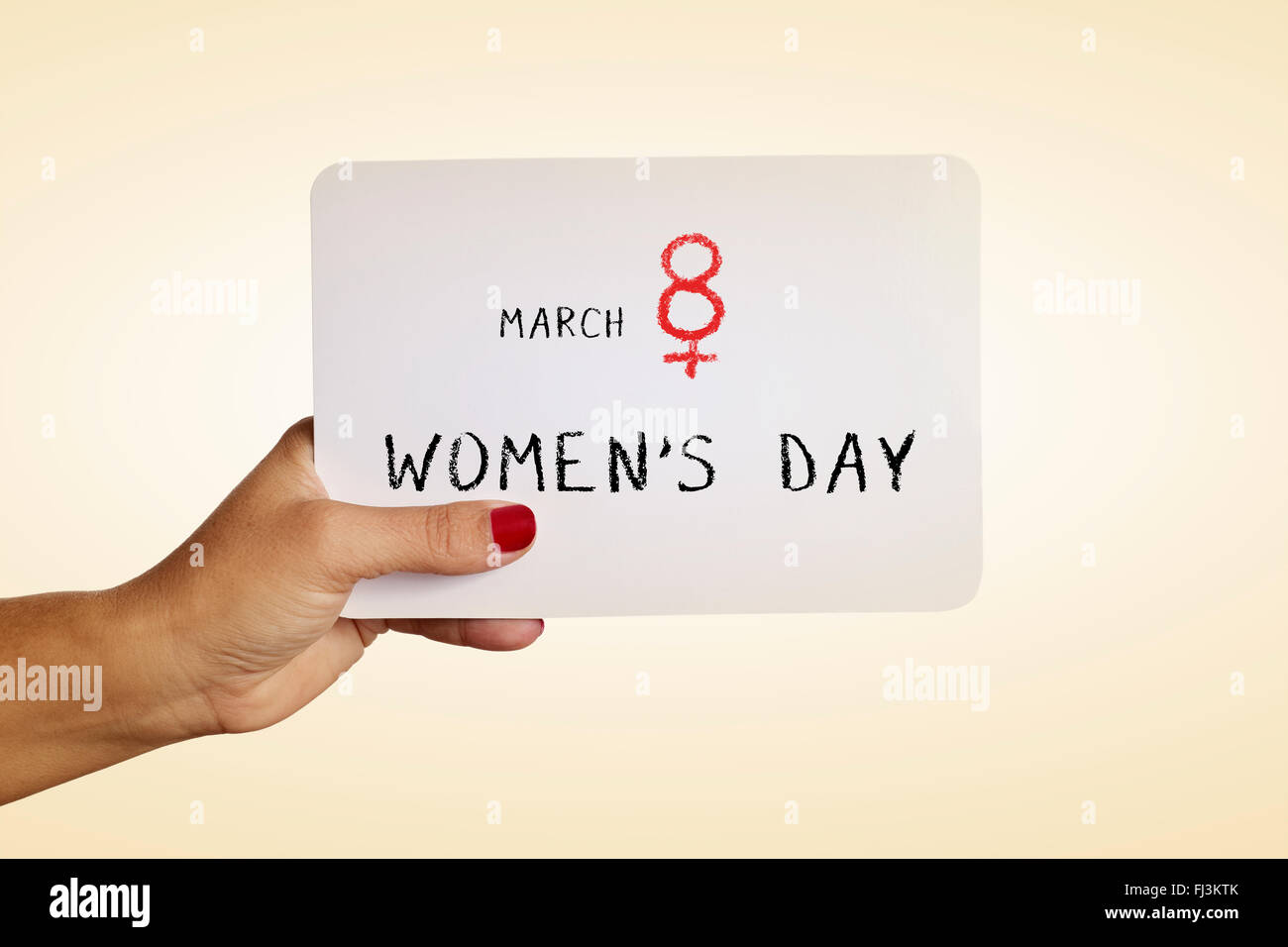 the hand of a young woman with red polished nails holds a signboard with the text march 8 womens day, with the number eight as t Stock Photo