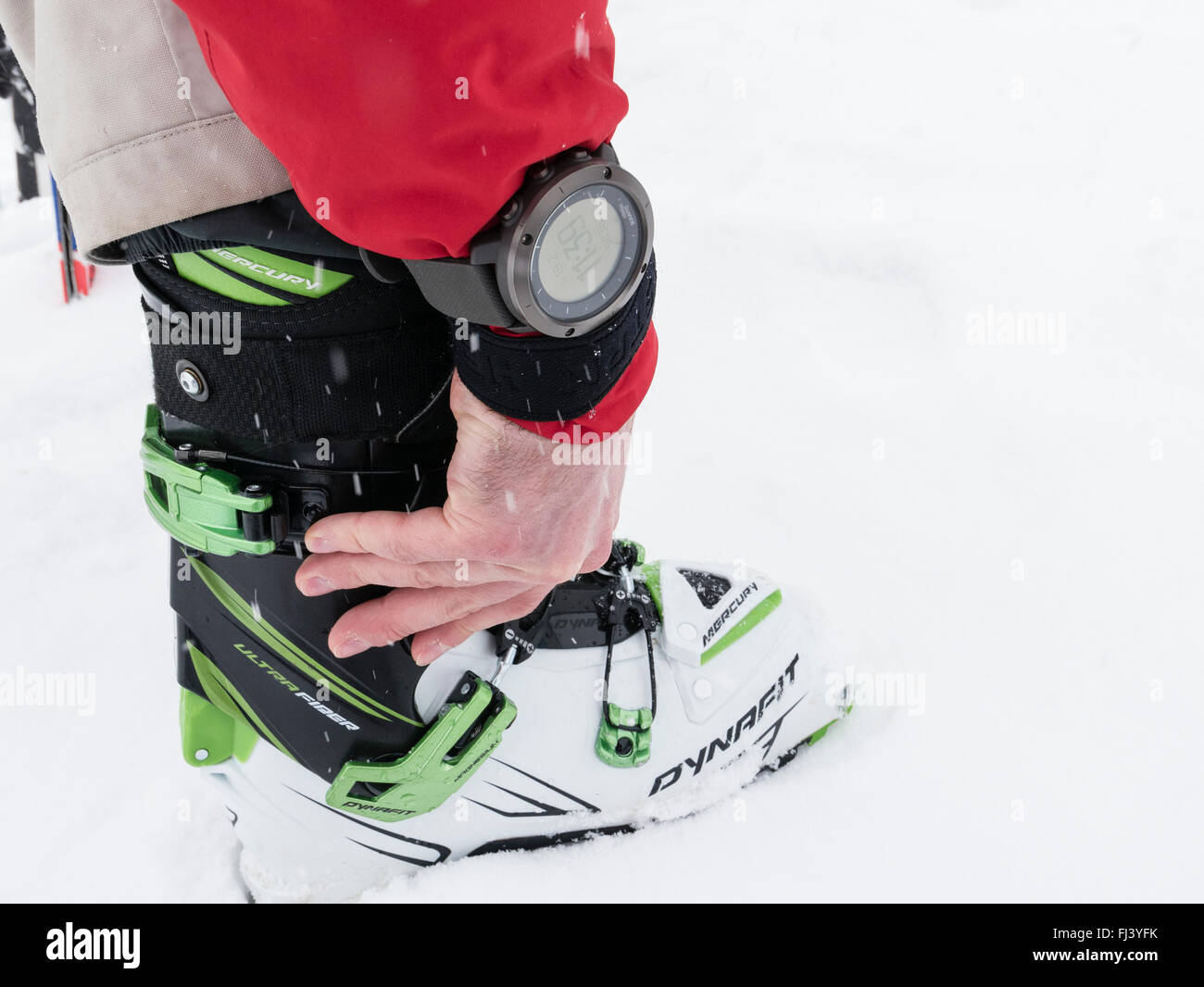 Skier adjusting Dynafit alpine touring ski boots and wearing a Suunto GPS Watch device for backcountry skiing navigation. Alps Stock Photo