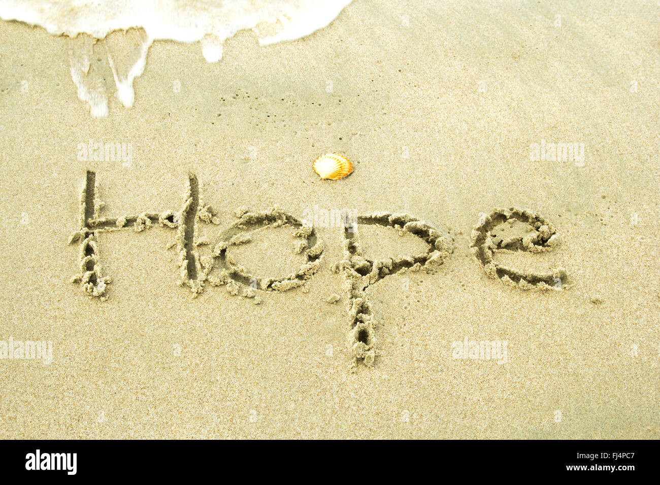 Word 'Hope' handwritten in sand at beach. Stock Photo