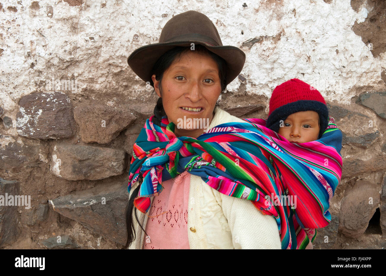 woman in traditional clothing carrying piggyback her baby in a sling, portrait, Peru, Pisaq Stock Photo