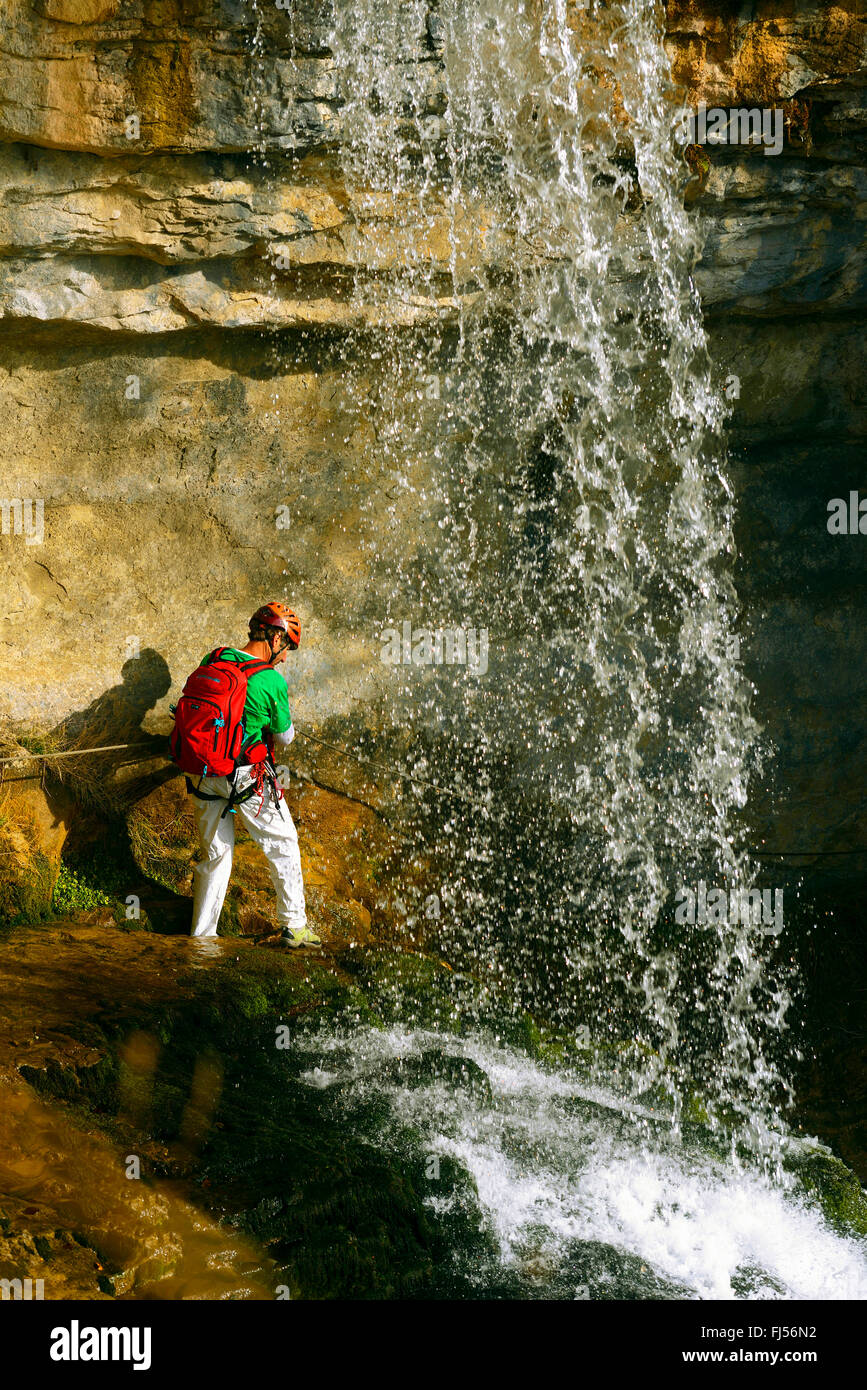 climber between rock face and waterfall, via ferrata Jules Carret, Grotte a Carret, France, Savoie, Chambery Stock Photo