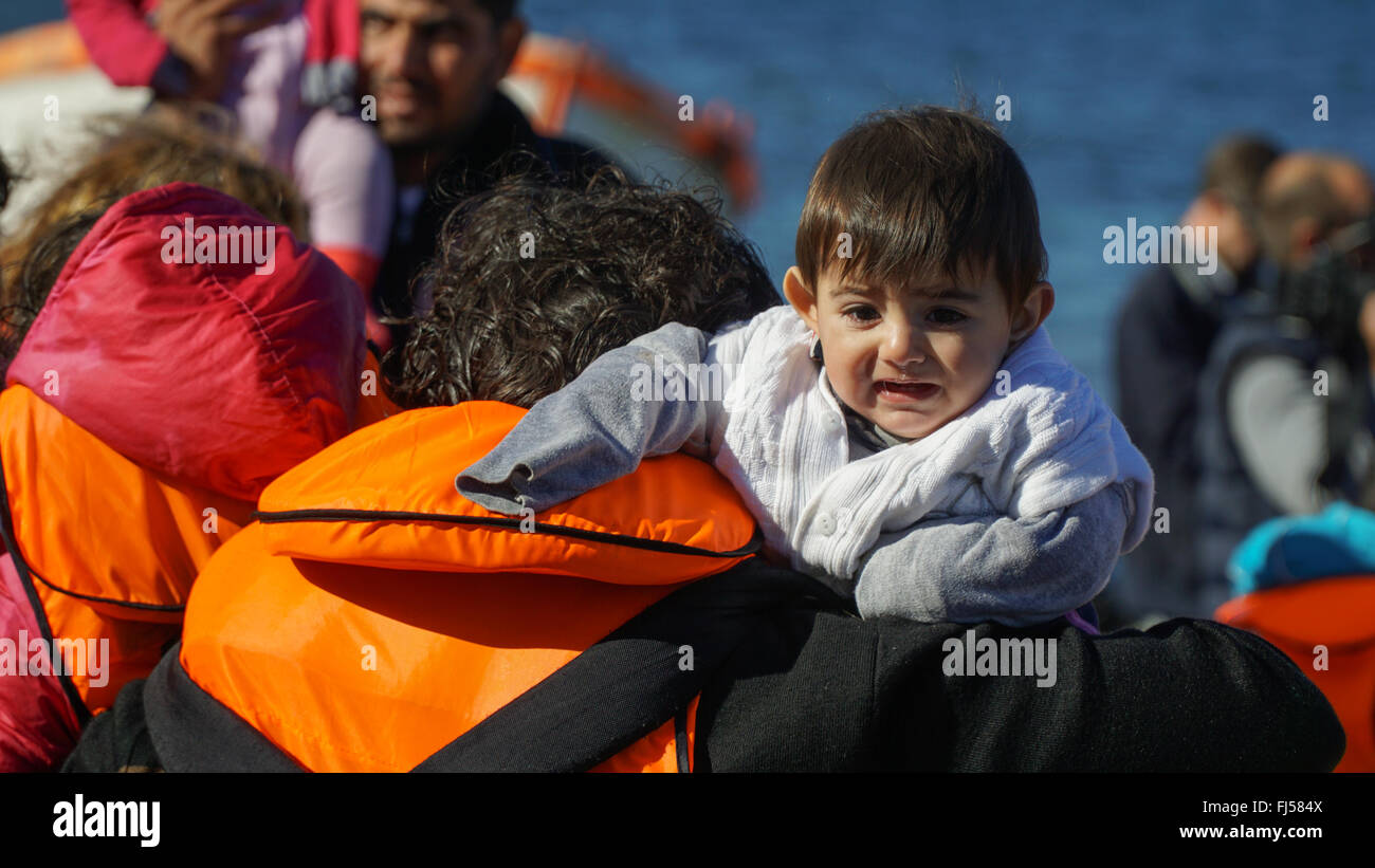 LESVOS, GREECE - October 13, 2015: Refugee child pulled out of the newly arrived boat from Turkey to the shore. Stock Photo