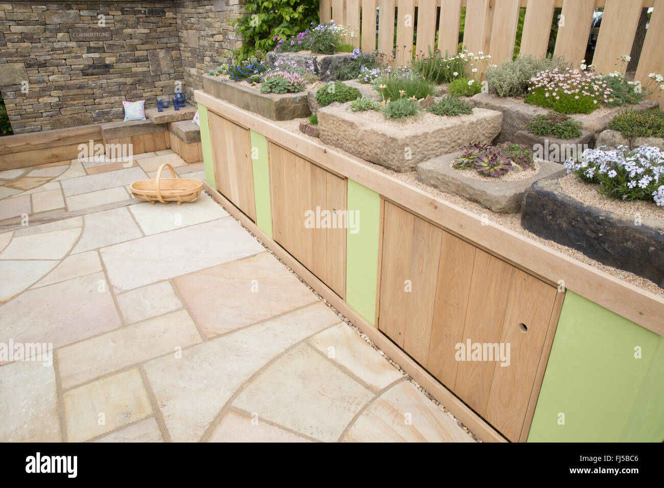 Small urban garden stone slabs patio storage cupboards a display of alpine plants in stone troughs containers container - seating area stone bench UK Stock Photo
