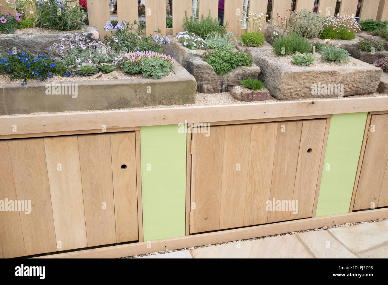 Small urban garden storage cupboards a display of alpine plants grown growing in stone troughs containers container UK Stock Photo