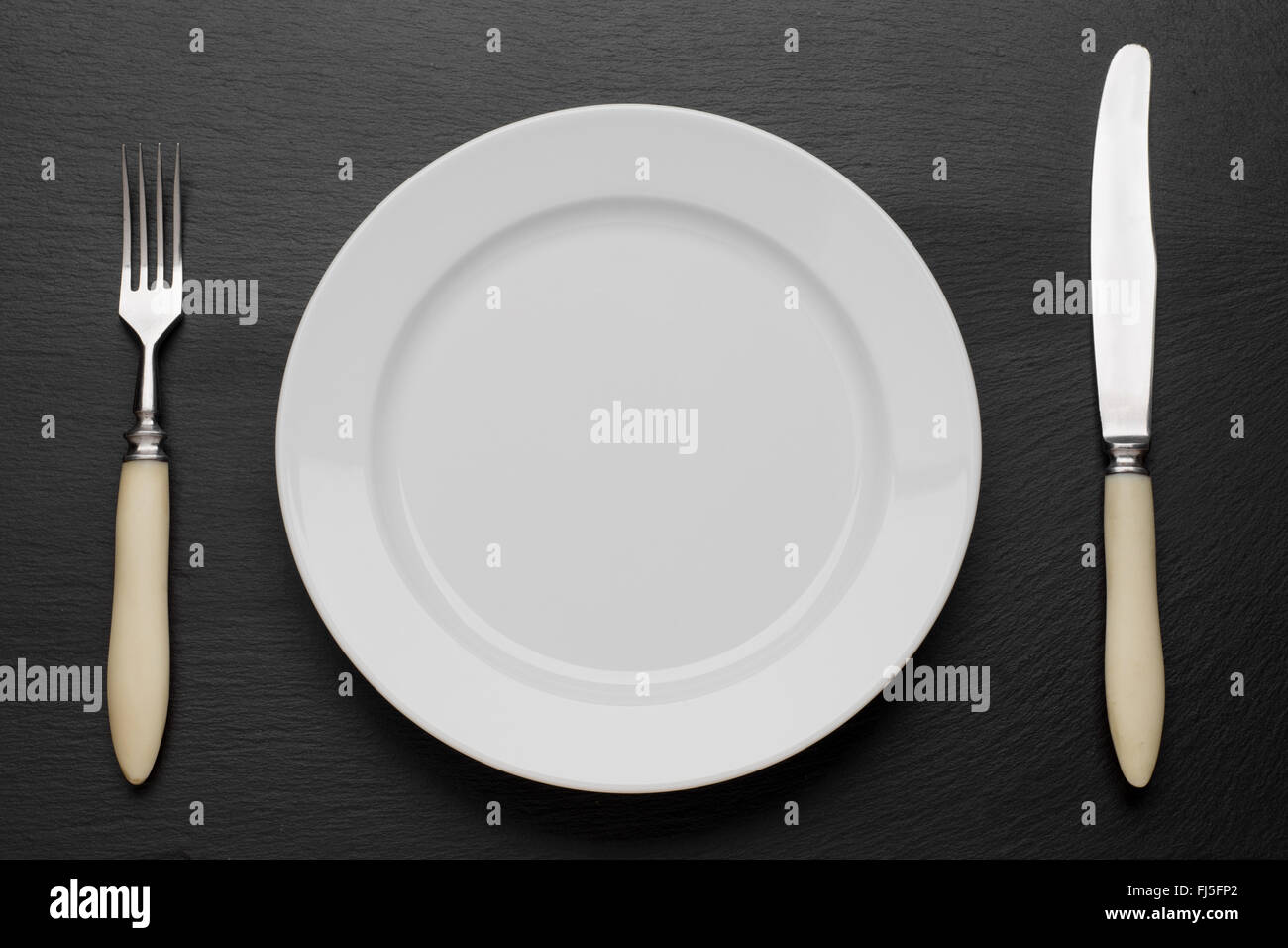 plate, knife and fork on table background Stock Photo - Alamy