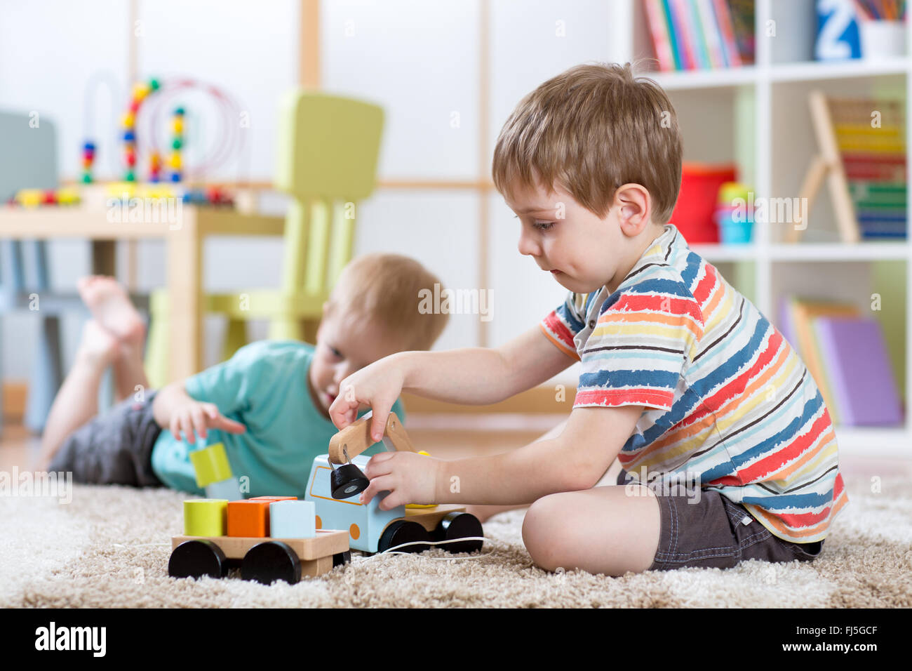 children boys toddlers playing with toy car indoors Stock Photo
