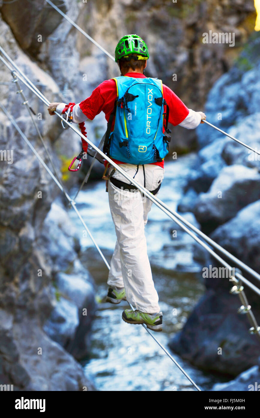 climber crossing the canyon on a suspension bridge, France, Hautes Alpes, Chateau Queyras Stock Photo